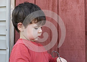 little boy playing with twigs in the backyard by the garage