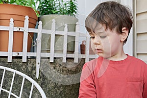 little boy playing with twigs in the backyard by the garage