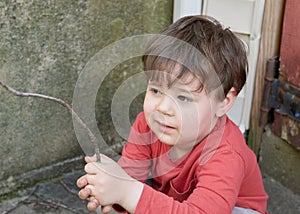 little boy playing with twigs in the backyard by the garage