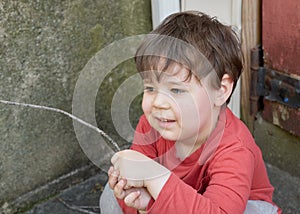 little boy playing with twigs in the backyard by the garage