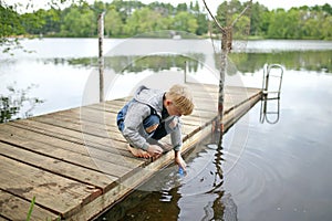 Little Boy Playing in the Water of Lake off Dock