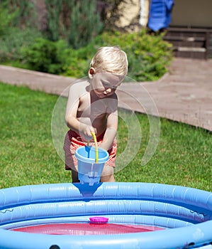 Little boy playing with water near the children's pool on the la