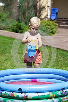 Little boy playing with water near the children's pool on the la