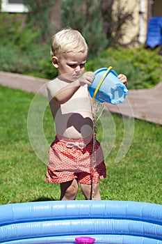 Little boy playing with water near the children's pool on the la