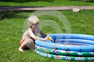 Little boy playing with water near the children's pool on the la