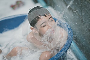 Little boy playing water splash at the backyard outdoor activities summer time