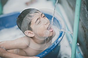 Little boy playing water splash at the backyard outdoor activities summer time