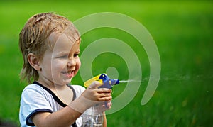 Little boy playing with water spray on hot summer day.