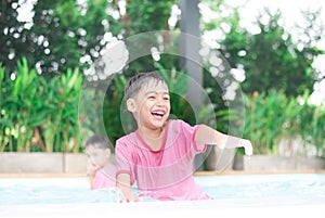 Little boy playing water at swimming pool in the hotel