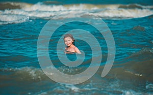 Little boy playing with Waves on blue sea. Cute boy having fun on a summer vacation in the sea.