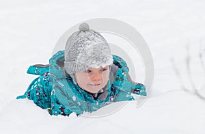 Little boy playing in the white fluffy fresh snow in winter.