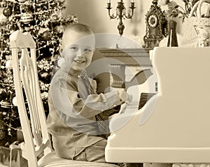 Little boy playing on a white Grand piano.