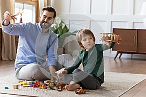 Little boy playing with wooden airplane, enjoying playtime with daddy.