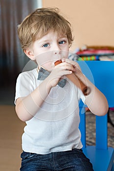 Little boy playing wooden flute indoor