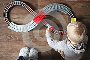 A little boy plays a children`s railway. Mom is watching her son from above. The child is fascinated by the train