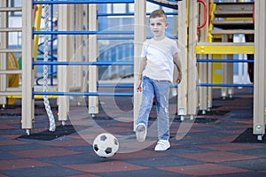 Little boy plays football on the park