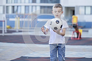 Little boy plays football on the park