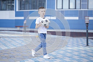 Little boy plays football on the park