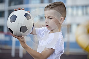 Little boy plays football on the park