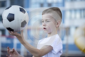 Little boy plays football on the park