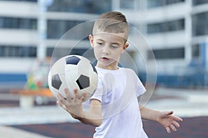 Little boy plays football on the park