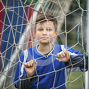 Little boy plays football on stadium. Sport.