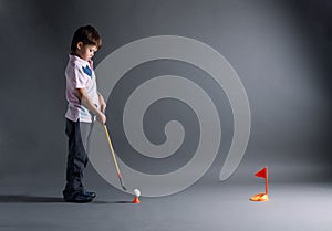 Little boy plays mini golf