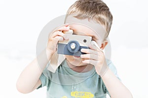 The little boy plays photographer with toy wooden camera