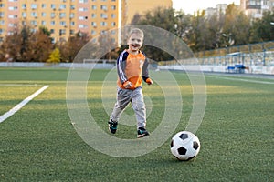 A little boy plays soccer in a city Park gives a pass kicks a ball