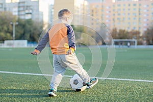 A little boy plays soccer in a city Park gives a pass kicks a ball
