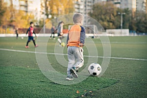 A little boy plays soccer in a city Park gives a pass kicks a ball