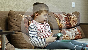 Little boy plays in video game on the couch at home on vacations