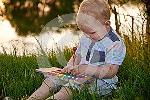 A little boy plays with a xylophone on the grass