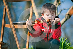 Little boy with pleasure eats grilled vegetables