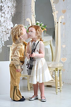 Little boy in pop retro suit kisses a girl
