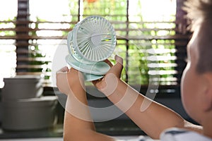 Little boy with portable fan at home. Summer heat