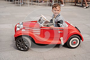 A little boy poses in a mini racing car. Play and relax in the fresh air.