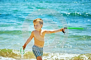 Little boy posing on the beach wearing snorkeling equipment. On the background of the sea