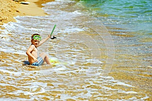 Little boy posing on the beach wearing snorkeling equipment. On the background of the sea