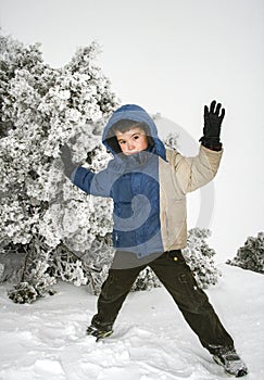 Little boy posing with hands up in a wintry snowy place photo