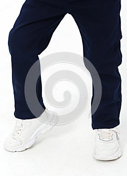 Little boy posing in school uniform - in trousers and white sneakers on a white background