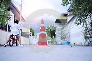 The little boy is practicing cycling a bicycle with the training wheels on the road