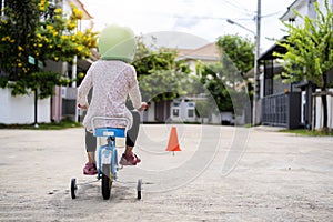 The little boy is practicing cycling a bicycle with the training wheels on the road