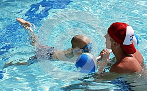 Little boy practicing kicks with swim instructor