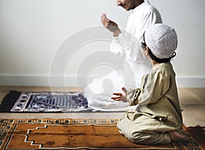 Little boy praying alongside his father during Ramadan photo