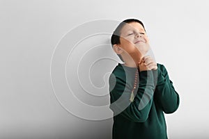 Little boy praying on light background