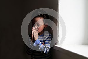 Little boy praying to God with hands held together stock photo