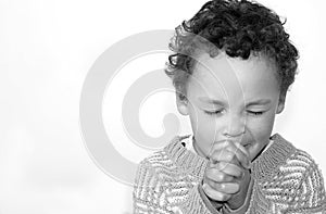 Little boy praying to God with hands held together stock photo