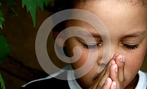 Little boy praying to God with hands held together stock photo