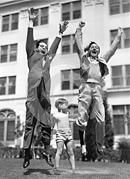 A little boy pretending to lift two grown men